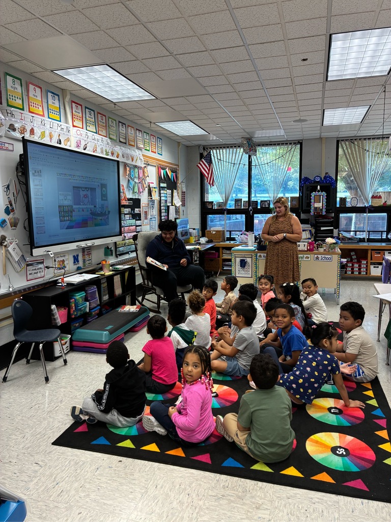 A high school student is reading to a class of kindergarteners