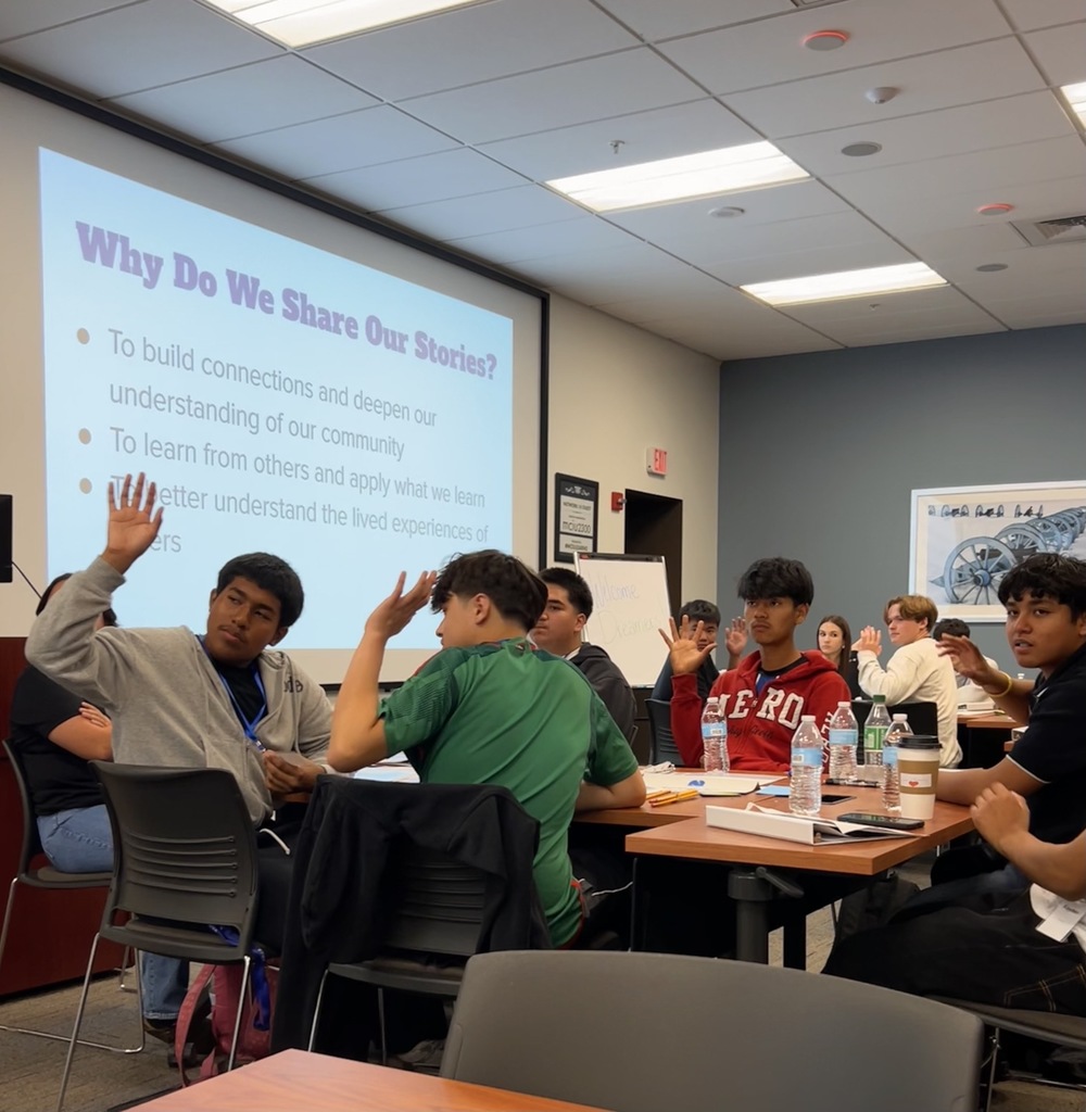 A table of students are raising their hands at the MCIU