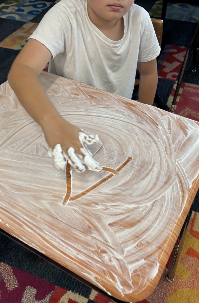 Students writing words in shaving cream for a sensory twist.