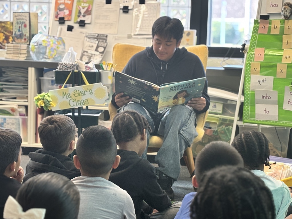 A student from NAHS reads a book to first grade students.
