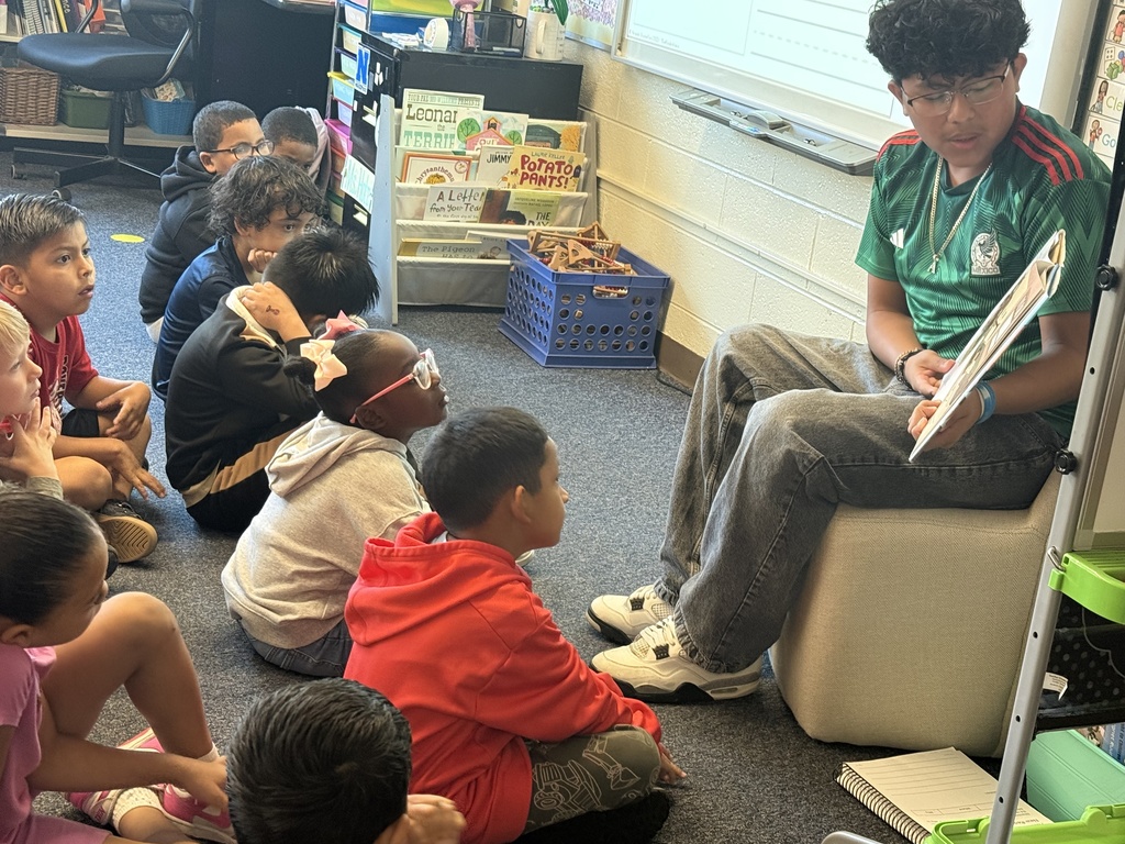 A student from NAHS reads a book to first grade students.