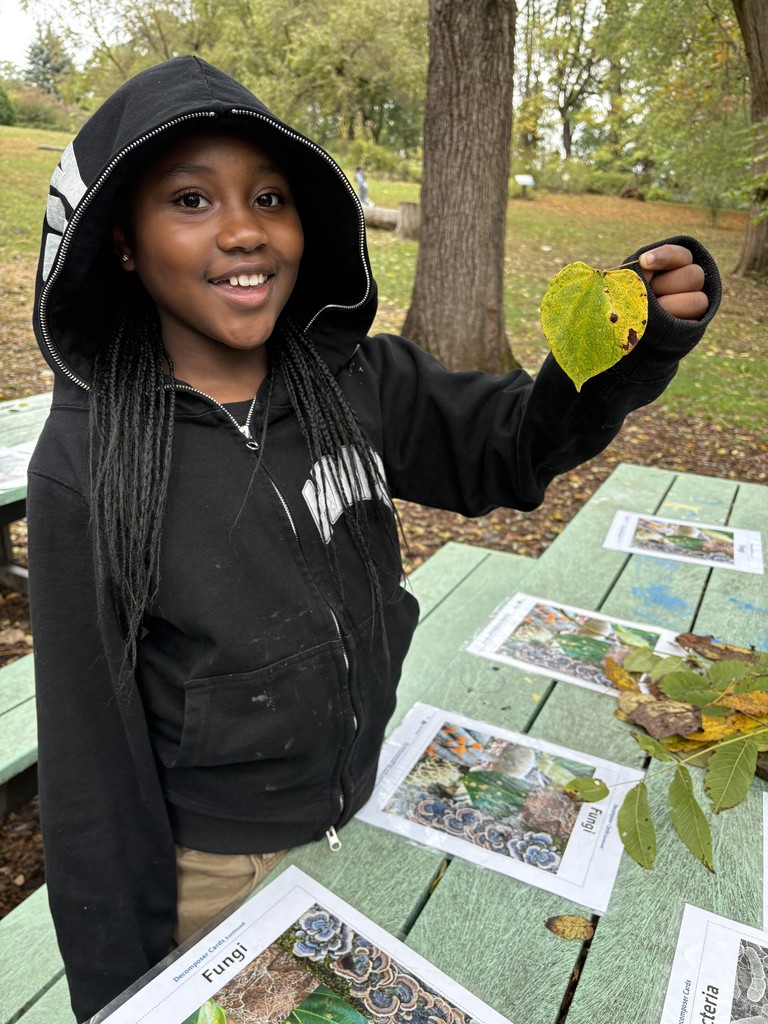 A fourth grader holds a leaf at Riverbend while learning about ecosystems.