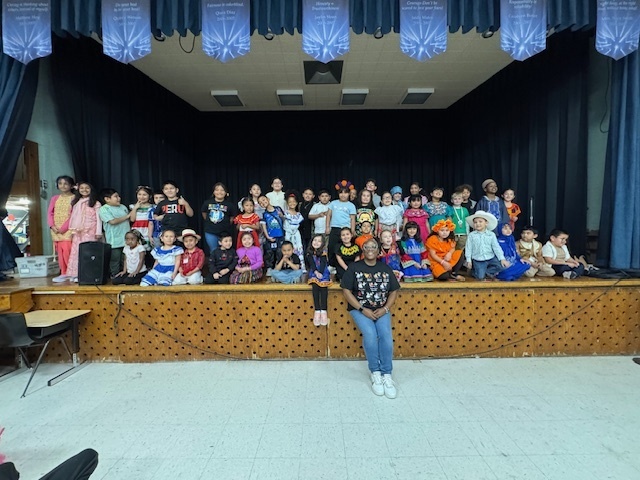 Students dressed in traditional clothing from their culture pose for a photo after the Hispanic Heritage Assembly.