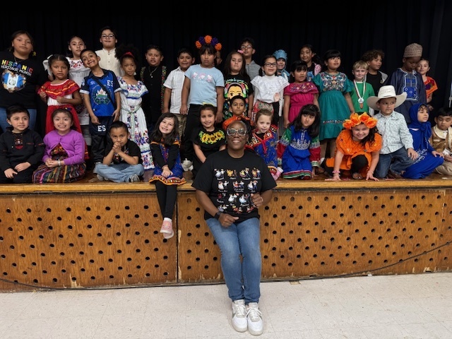 Students dressed in traditional clothing from their culture pose for a photo after the Hispanic Heritage Assembly.
