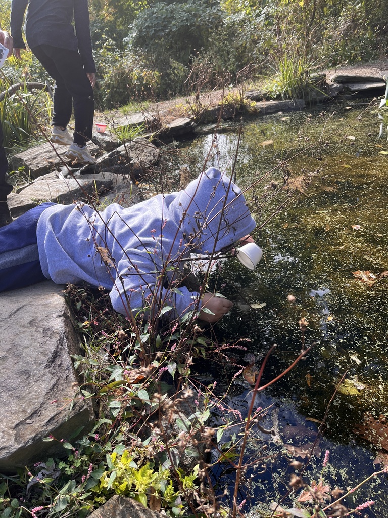 A student getting water out of the pond