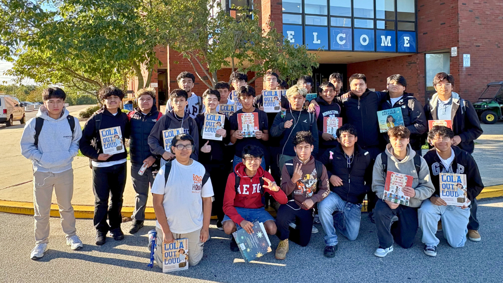 Students in Raices Encontradas club pose for group photo in front of NAHS holding books they will read in elementary classrooms.