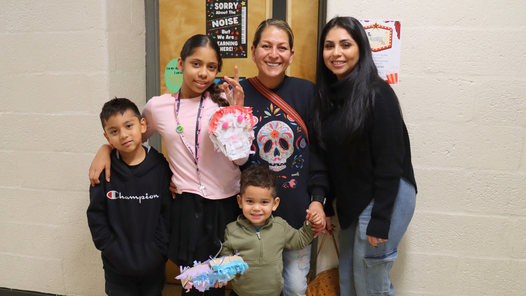 Family poses for a photo holding their home-made piñata during Hispanic Heritage Night.