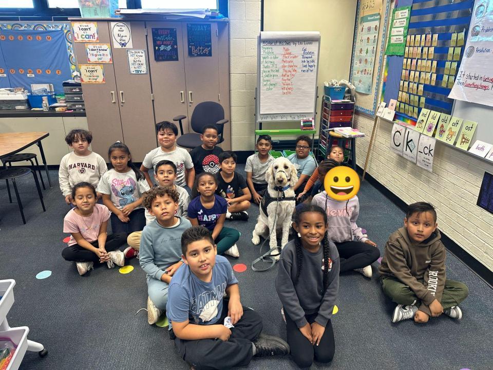 Students pose for a photo with Nutmeg the therapy dog.