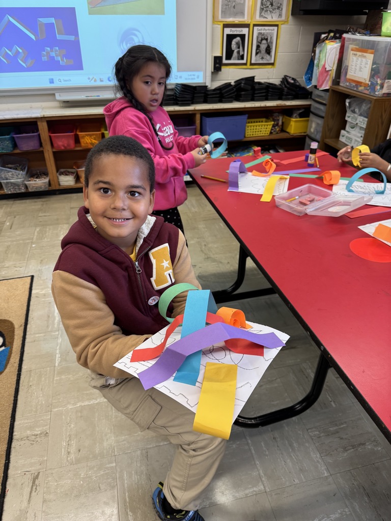 A kindergartner shows his rainbow paper line sculpture.