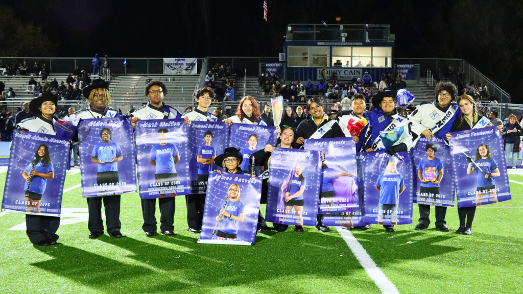 Senior band members pose for photo on the turf field.