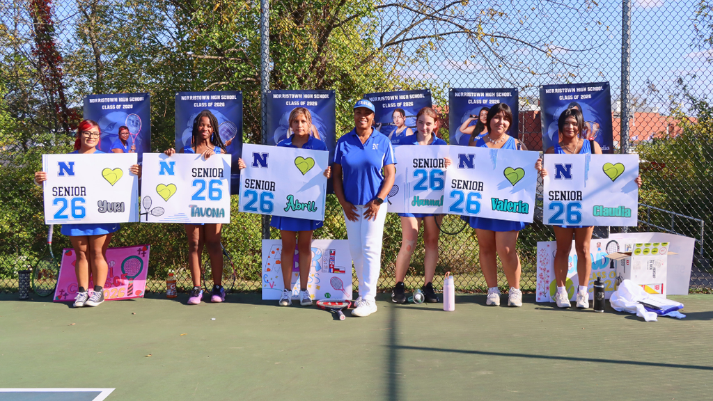 Six seniors from Girls Tennis holding their senior posters posing for a photo with their coach.