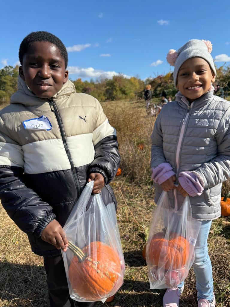 Students hold their apples and pumpkin.