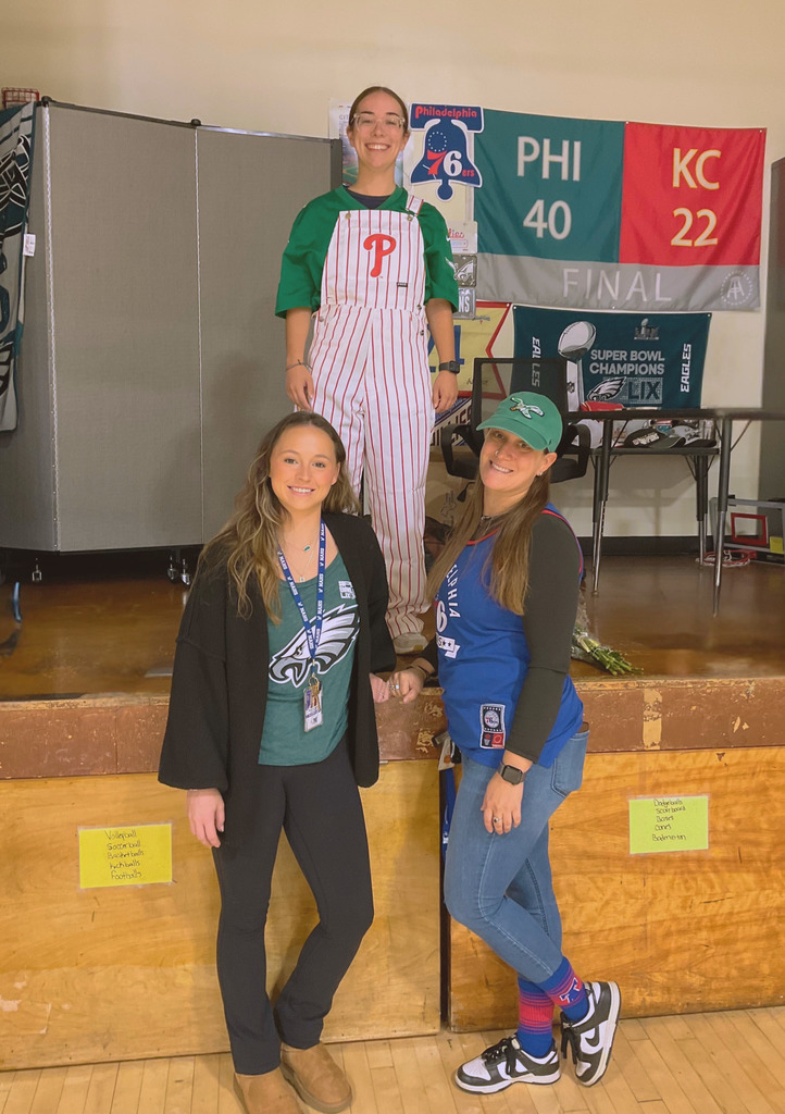 Three teachers pose in their Philly sports gear for sports spirit day.