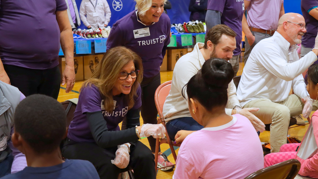 Truist volunteer gives a first bump to student before getting fitted for new shoes.