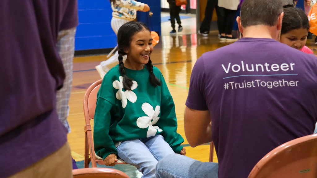 Student smiling as volunteer gets her shoes ready.