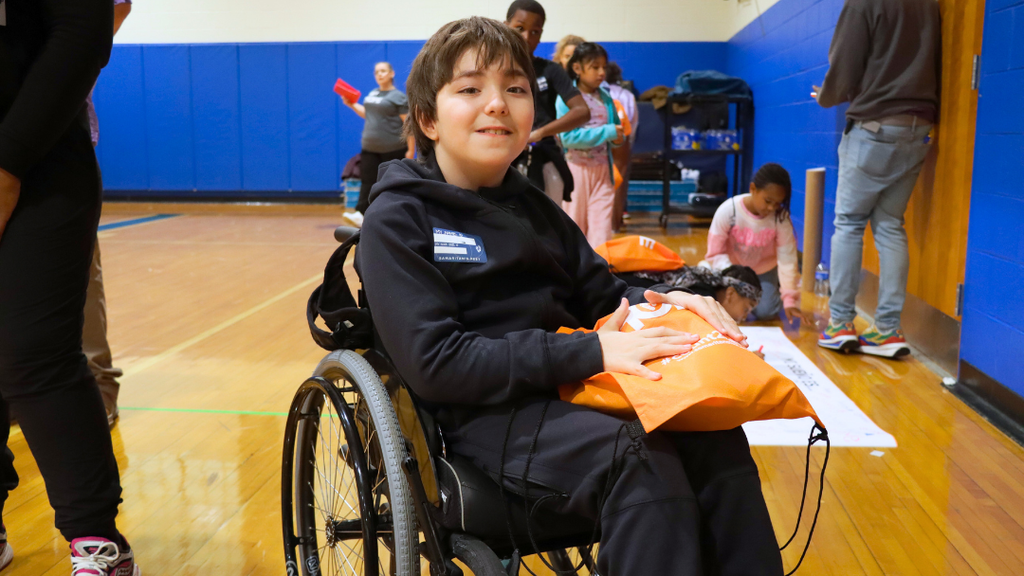 Student poses for a photo with his bag that has his new shoes.
