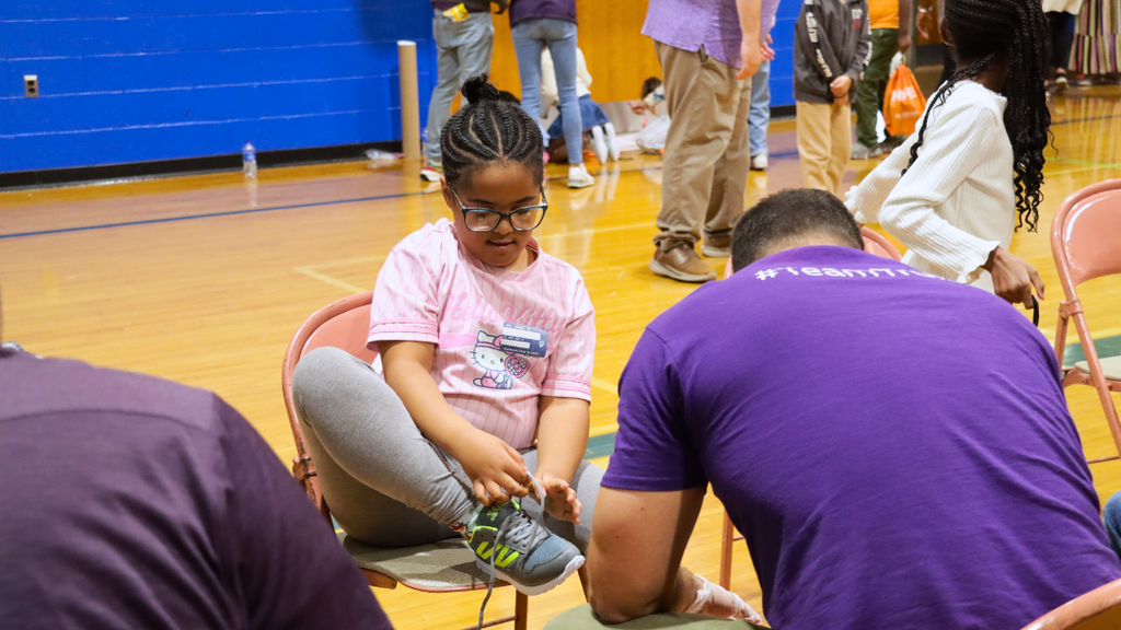 Student tying her shoelace of her new shoes.