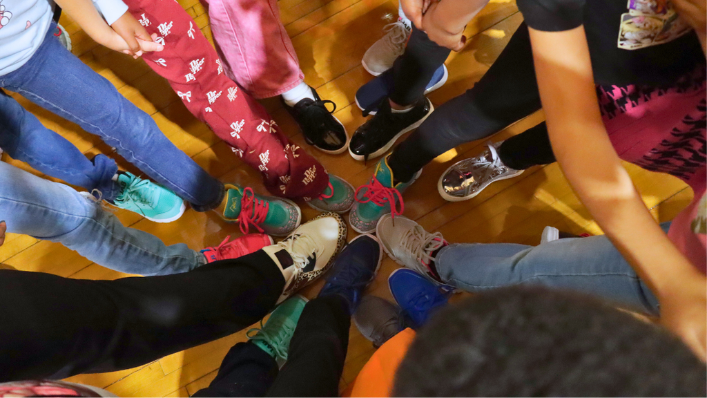 Group of students in a circle with a foot put in the middle of the circle.