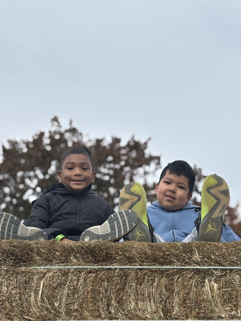 Two students sitting on hay at the farm