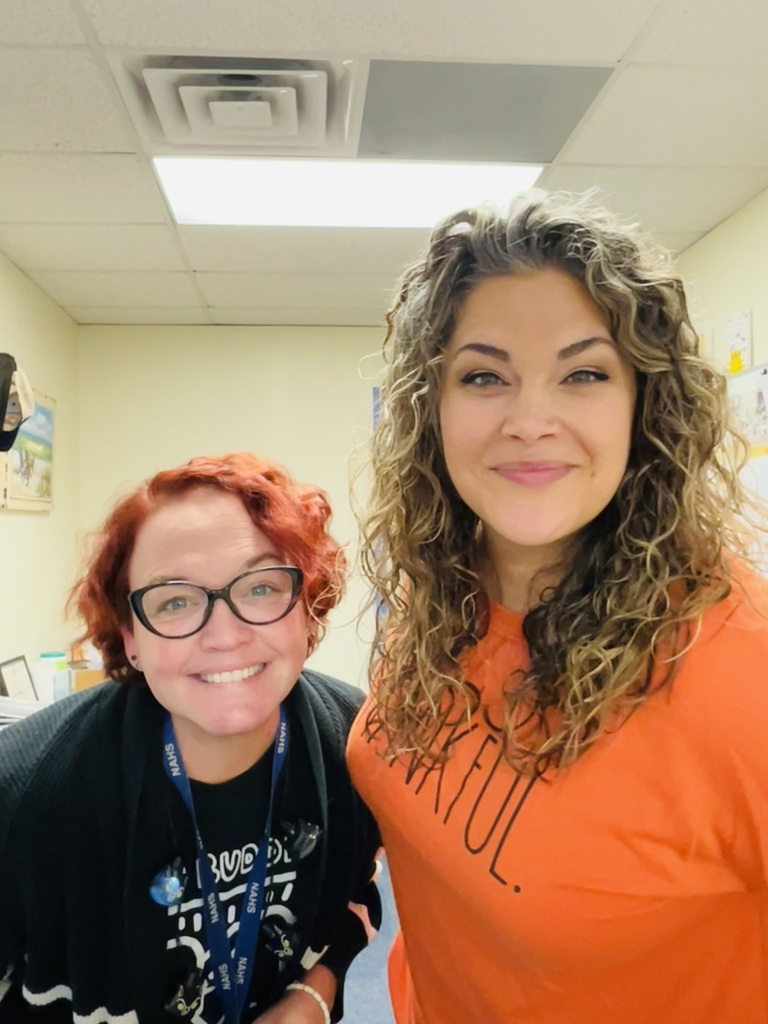 The counselor and a teacher pose together in their black and orange