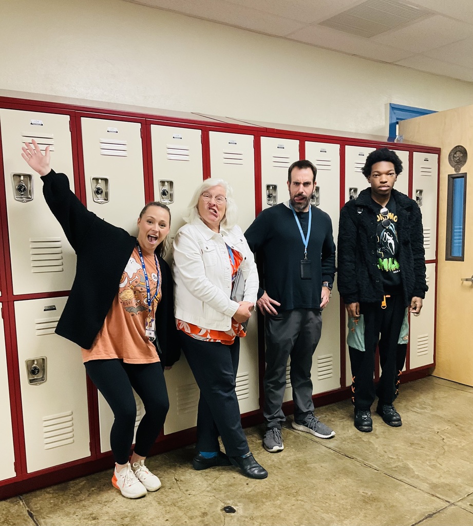 Three adults and one student pose for a picture together in front of lockers