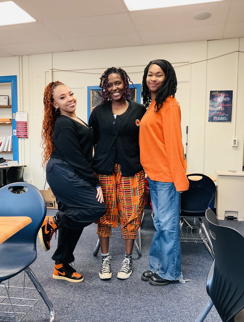 Three adults are showing their orange and black for spirit day