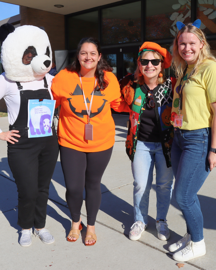 Four teachers dressed in Halloween costumes pose for a group photo.