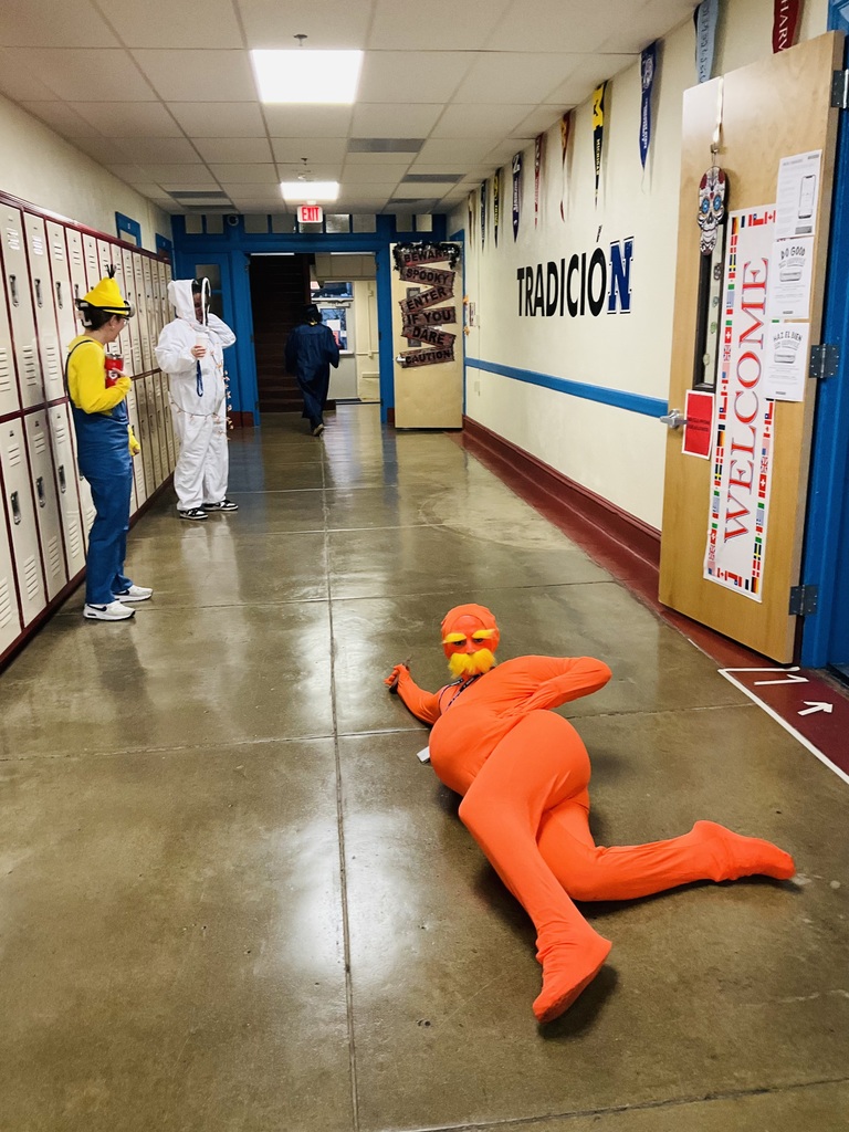 A teacher in a Lorax costume is laying on the ground in the hallway