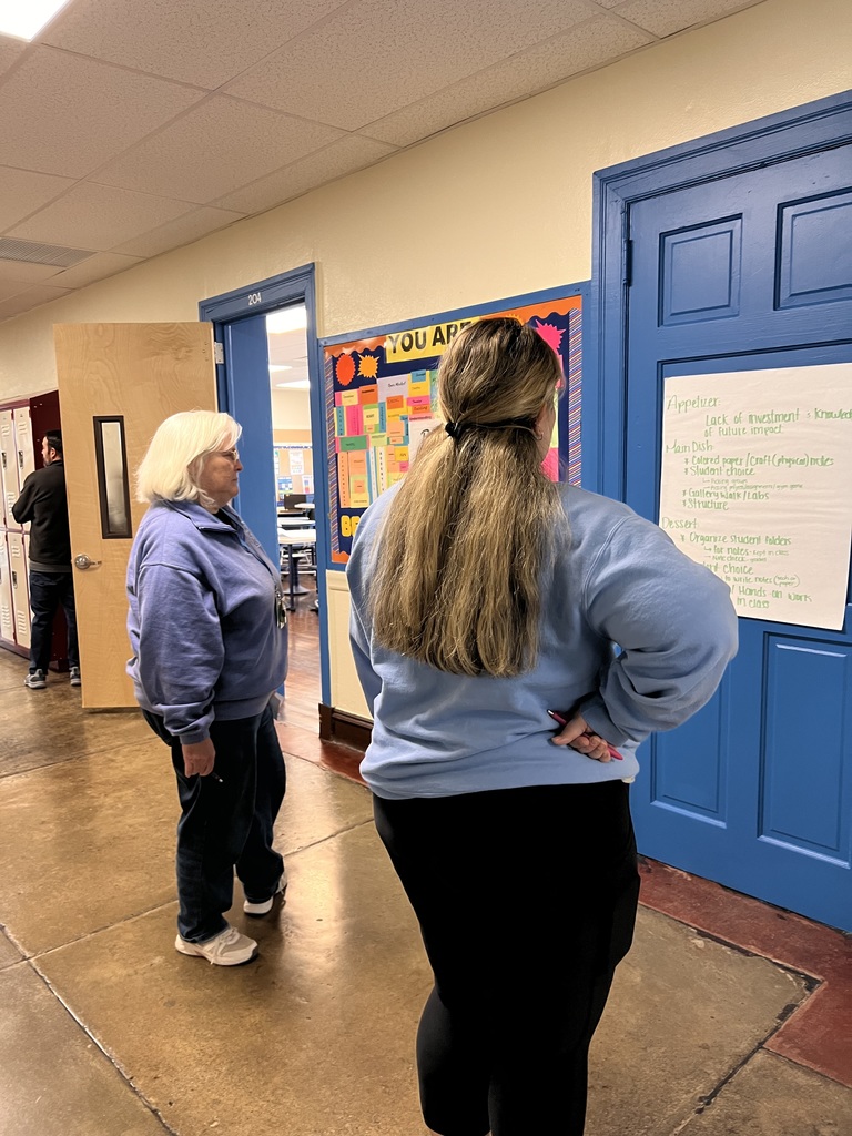 Two teaching are looking at a poster in the hallway as a part of a gallery walk