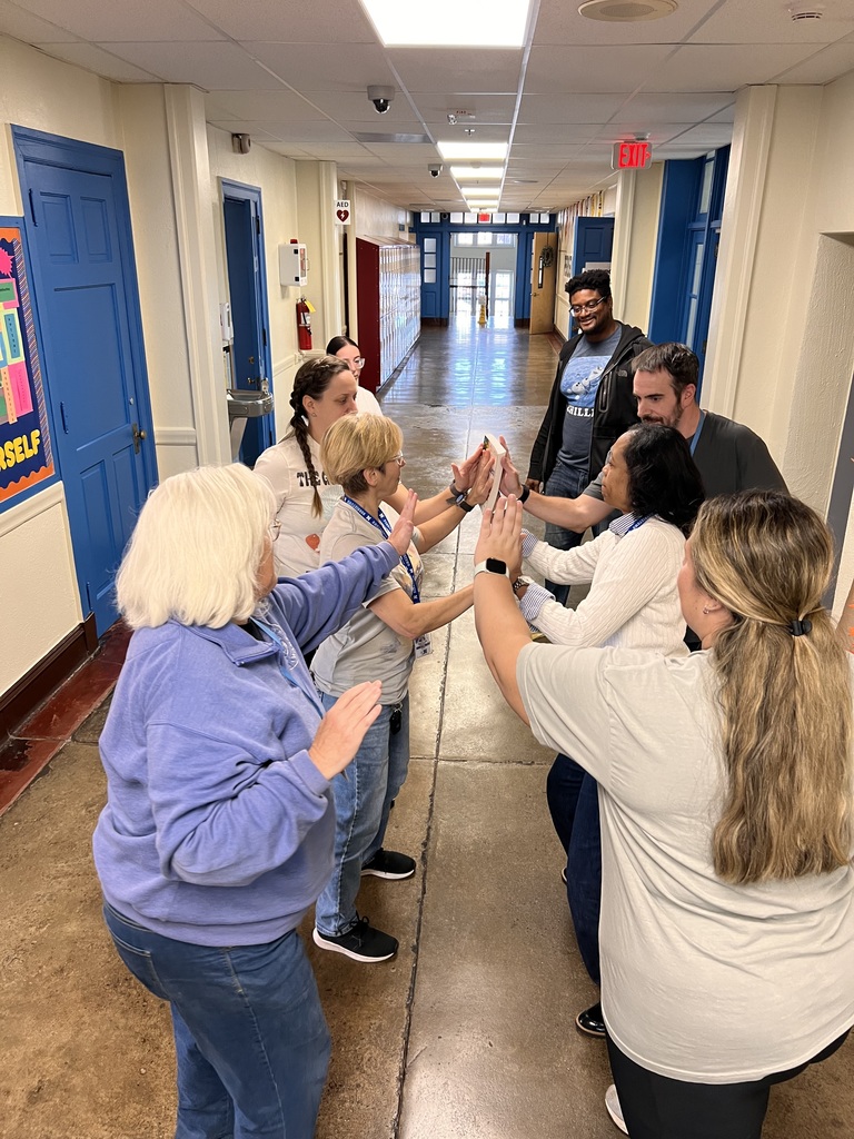 Teachers are participating in a brain break activity in the hall