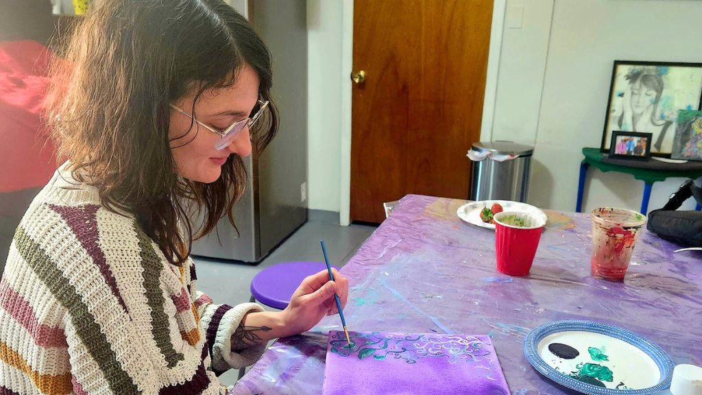 Teacher painting a purple canvas.