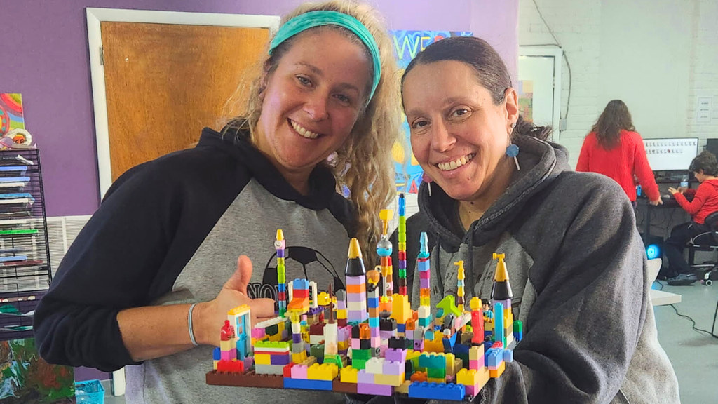Two teachers pose for photo with their lego building creation.