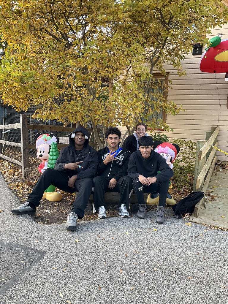 3 boys and a teacher are sitting together for a picture