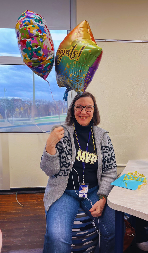 The community liaison is posing with balloons as she was just named the team member of the month.