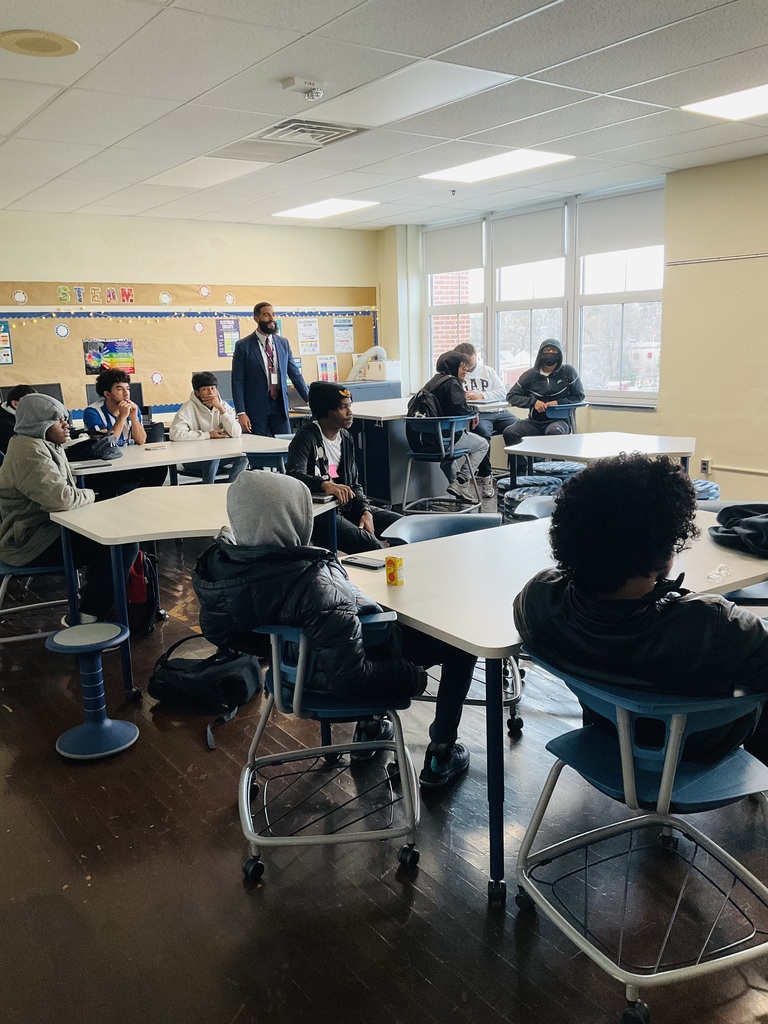 Numerous students are in a classroom listening to a presentation