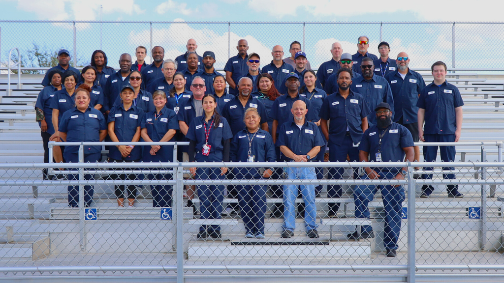 NASD custodians pose for large group photo on bleachers. 