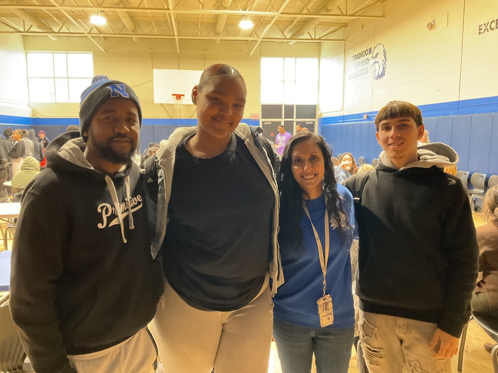 Two teachers and two students pose together for a picture in the cafeteria