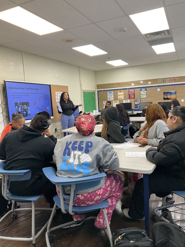 A group of students are listening to a presenter give a speech about nursing