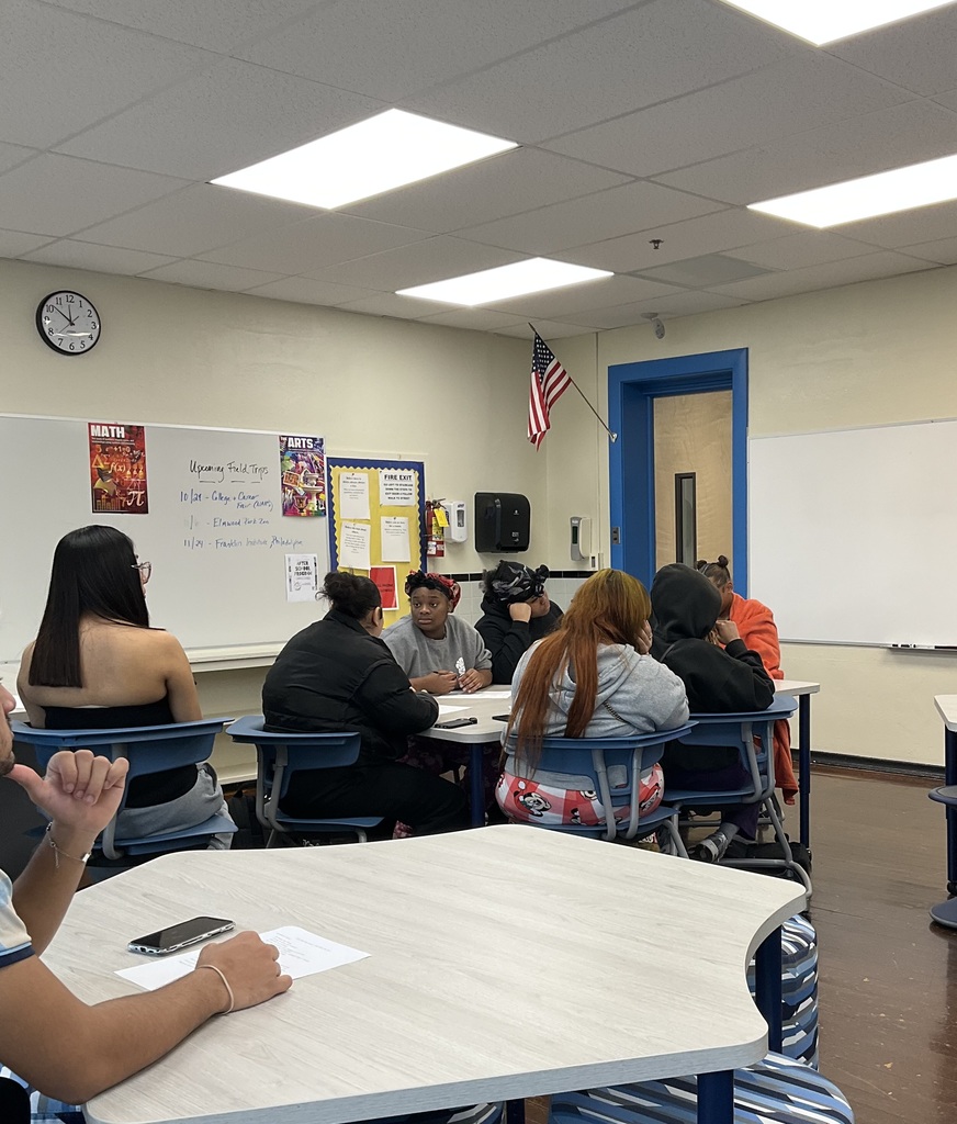 A group of students are listening to a presenter give a speech about nursing In a classroom