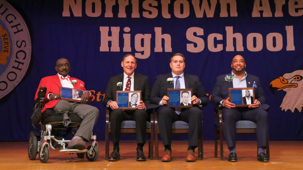 Hall of Fame Inductees sitting on stage holding their plaques. 