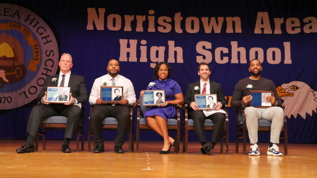 Hall of Champions Inductees sitting in chairs on stage for group photo. 