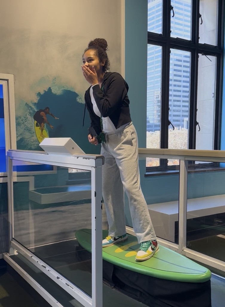 A student is on the surfboard simulator at the museum