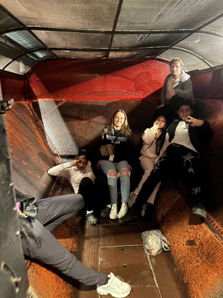 Multiple students and a teacher are inside of an exhibit together at the Franklin institute