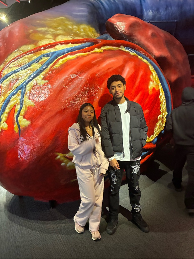 Two students are posing outside of the giant heart display at the Franklin institute