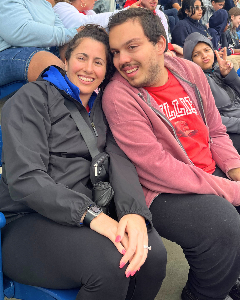 Student and staff member pose for photo during the Phillies baseball game. 