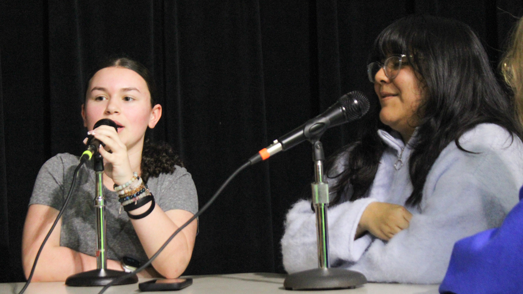Two students speaking into microphones. 