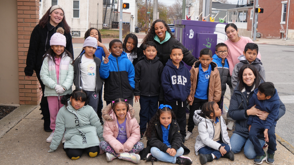 Students, teachers, and artist Nessie Blaze pose for group photo in front of the traffic box.