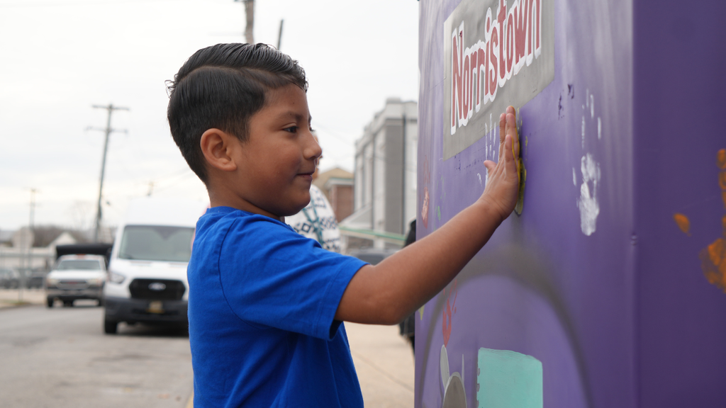Student pressing their hand against the box to leave their handprint. 