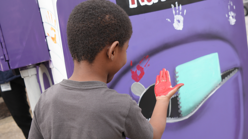 Student looking at their handprint after putting it on the traffic box.