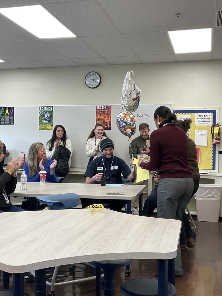The custodian is surrounded by colleagues as he was just named the team member of the month